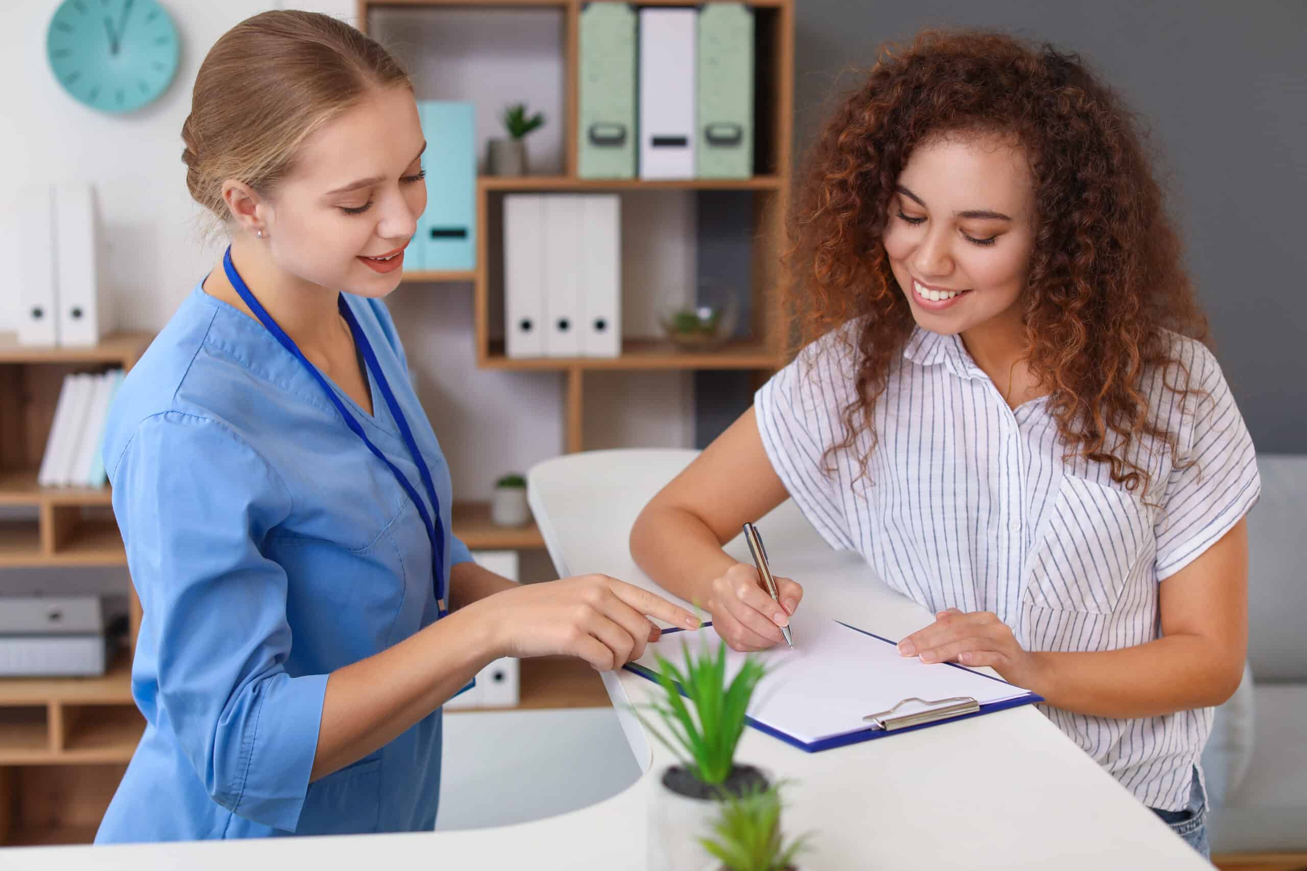 Young female receptionist working with patient in clinic