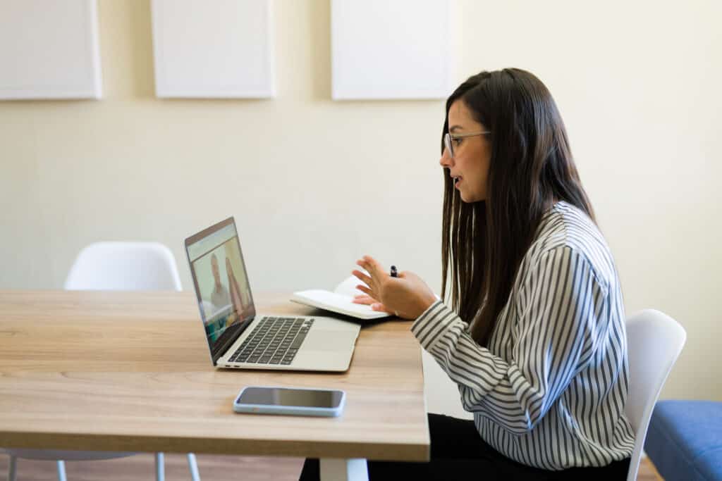 Psychologist talking with a couple during virtual therapy session on laptop, providing support and guidance remotely