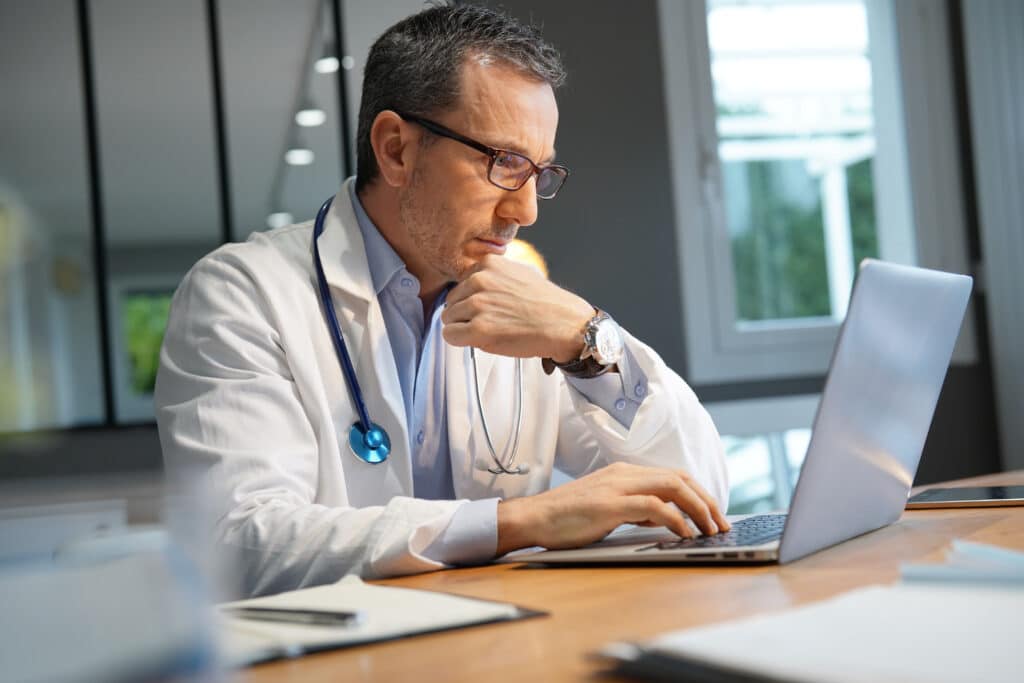 Doctor in office working on laptop
