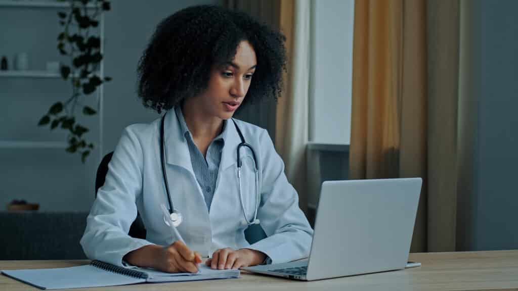 African woman specialist doctor therapist practitioner advisor in clinic talking by video call consulting patient online health therapy distance medical communication virtual treatment write diagnosis. High quality 4k footage