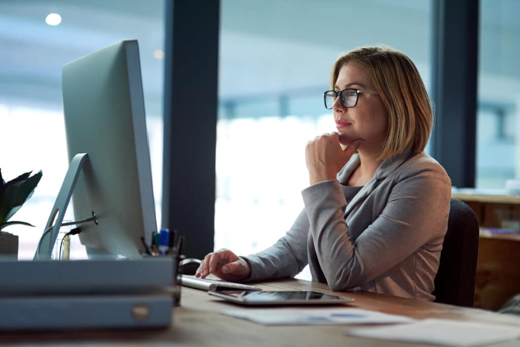 Computer, thinking and business woman in office working late on project at night alone. Desktop, professional and female person problem solving, focus or solution, planning or reading on deadline.