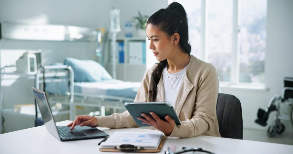 Receptionist, laptop and tablet with woman in hospital for medical files, doctor letter and researcher. Healthcare, surgery schedule and telehealth appointment with person in clinic for online admin.