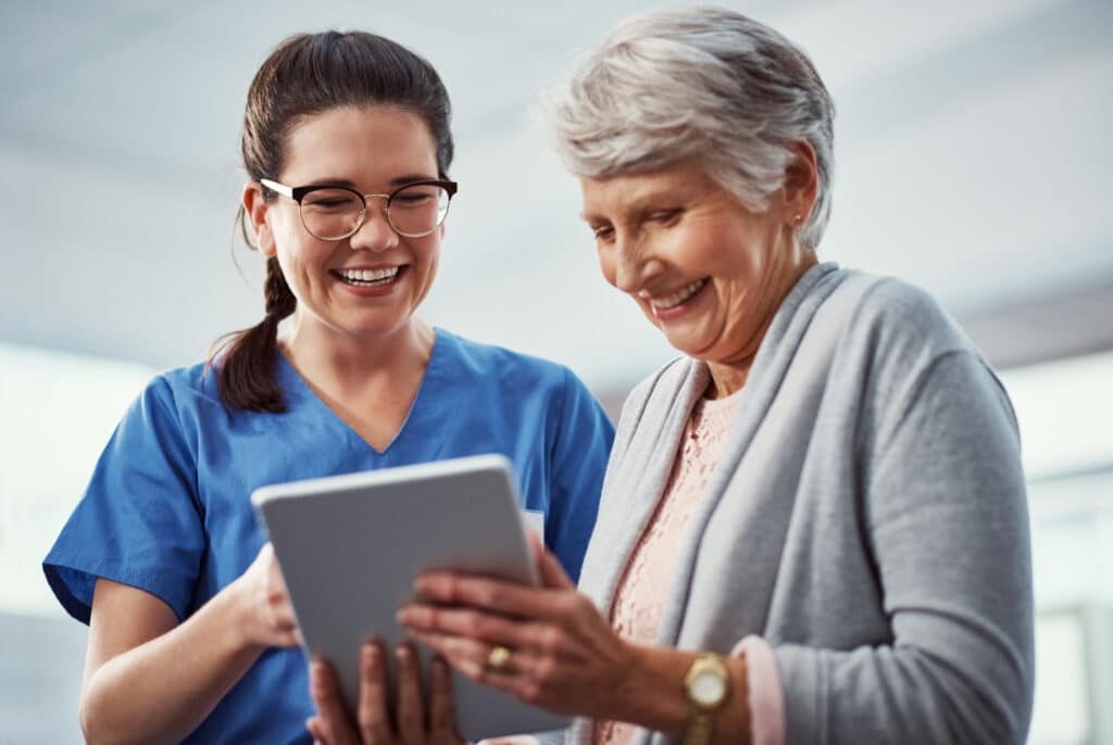 Happy, tablet and nurse with senior woman in clinic for online results, diagnosis and consulting. Laugh, hospital and person with elderly patient on tech for report, medical service and healthcare.