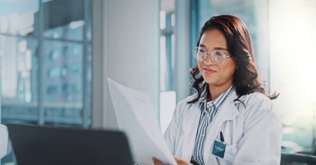 Woman, doctor and smile with paperwork or laptop for research or study results and feedback. healthcare, medical and happy or satisfied with document for medicine or patient information in office.