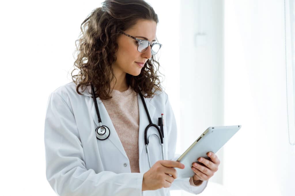 Portrait of female doctor using her digital tablet in the consultation.