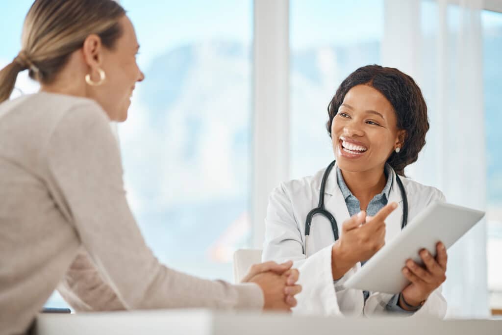 Doctor with patient and tablet showing lab results, good news for health insurance or medical cure in consultation visit or appointment. Healthcare worker with digital report giving advice to patient.