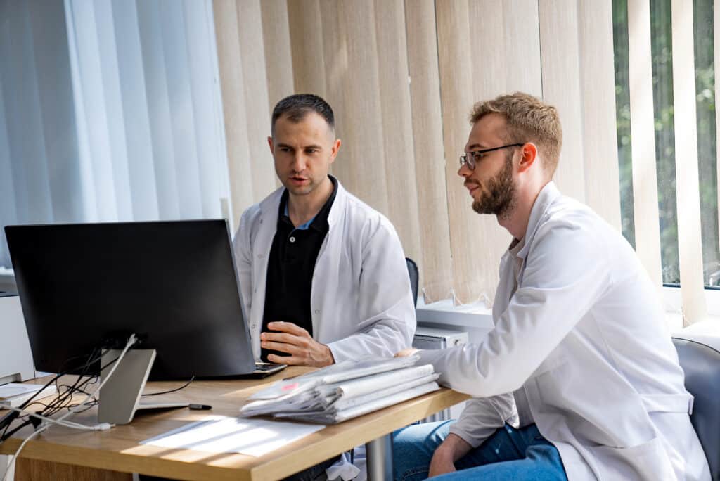 Two Doctors Working On Computer in Office. Two doctors in a medical office discuss something on a computer.