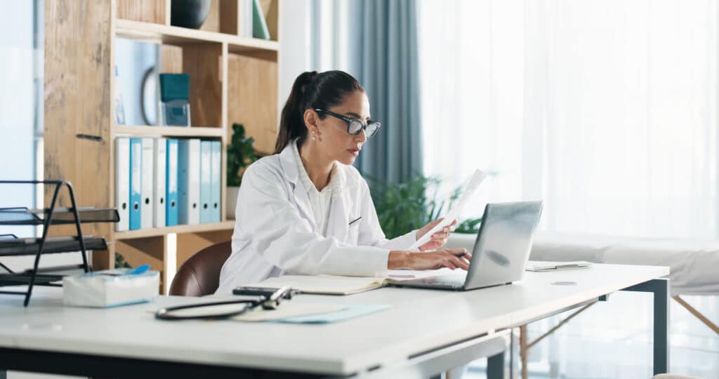 Doctor, laptop and woman with paperwork in office for clinic admin, diagnostic info or medical report. Healthcare, expert and reading health website for treatment plan, results comparison or research.