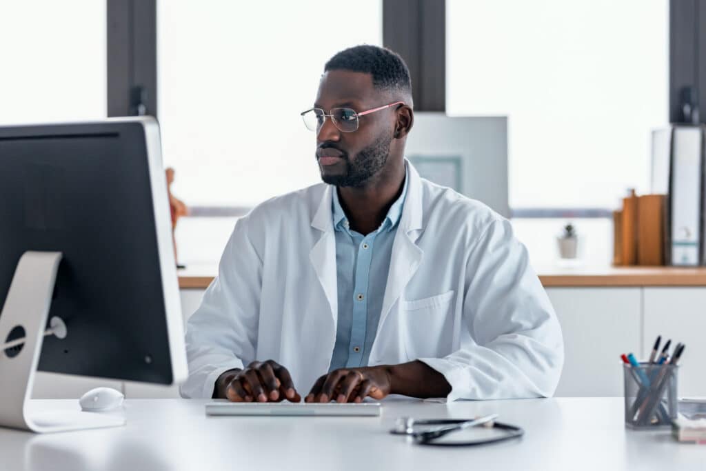 Shot of smart male doctor working with computer in the medical consultation