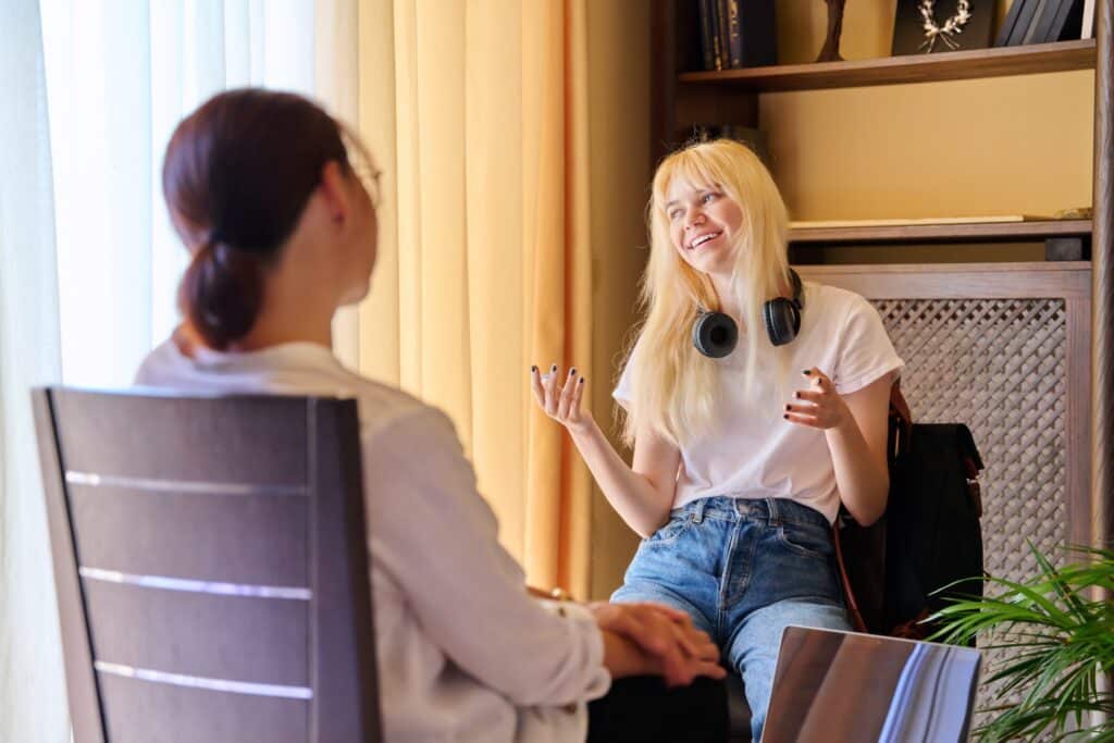 Teenage female in therapy session in psychologist's office, young woman talking about problems. Psychology, mental health, psychiatry, care, youth concept.