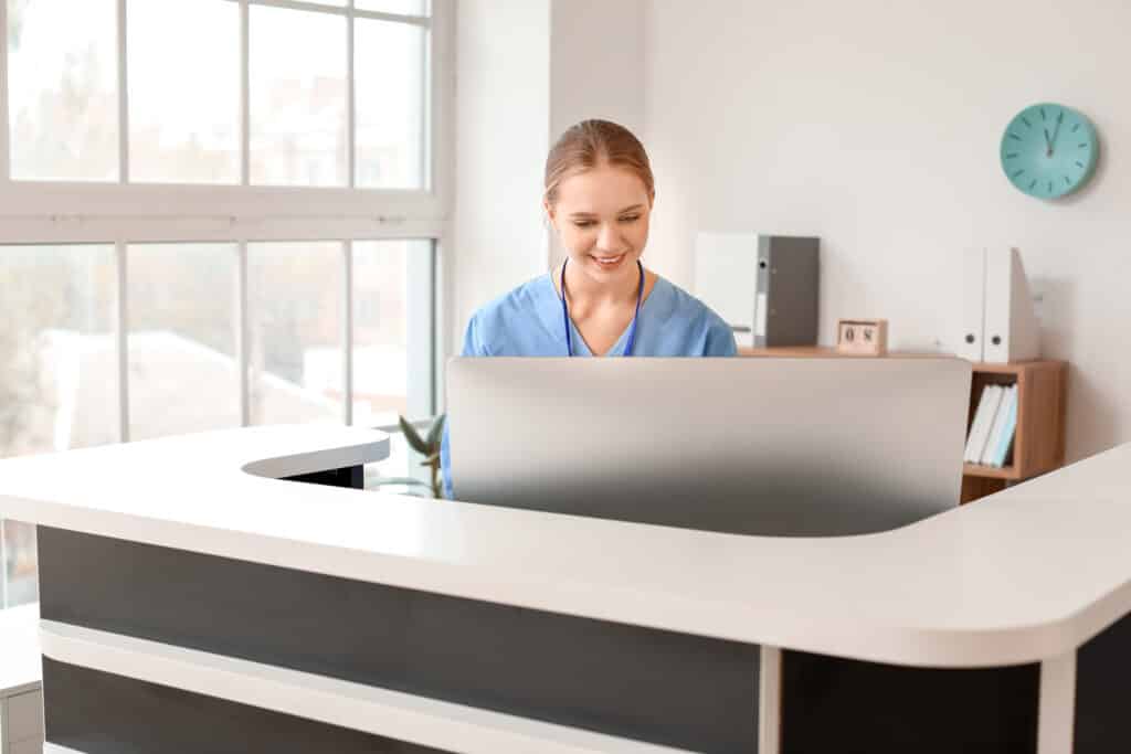 Young female receptionist working at desk in clinic