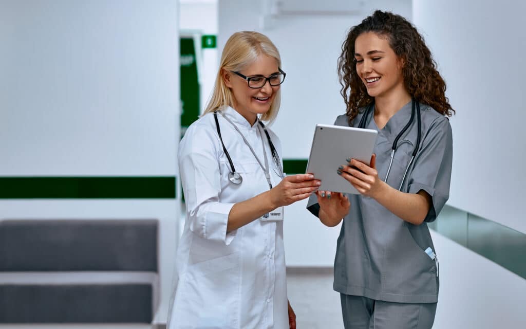 Doctors laugh and talk in the hallway. Older woman and young female doctors.