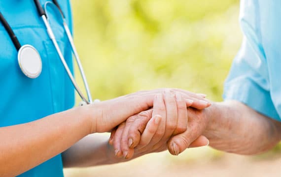Nurse holding elder man hands for CCM services.