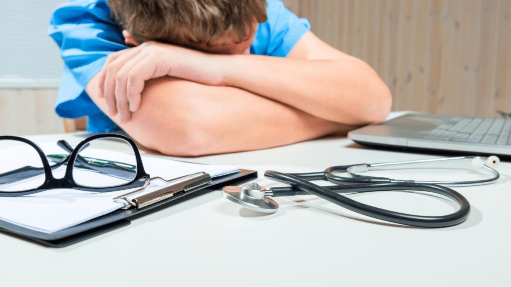 Physician taking a nap on work desk in front of laptop