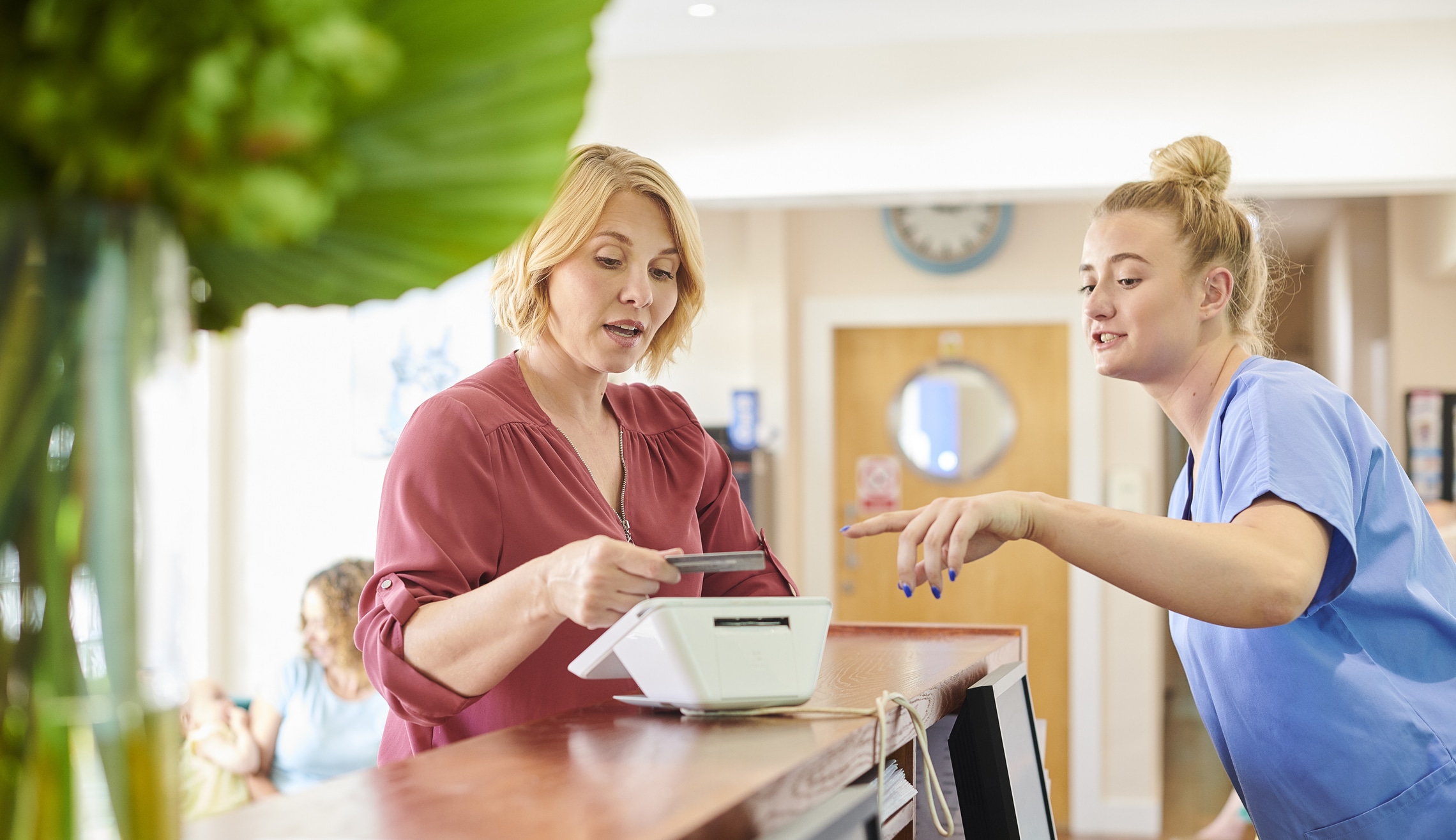 female patient chats to the nurse whilst paying at reception
