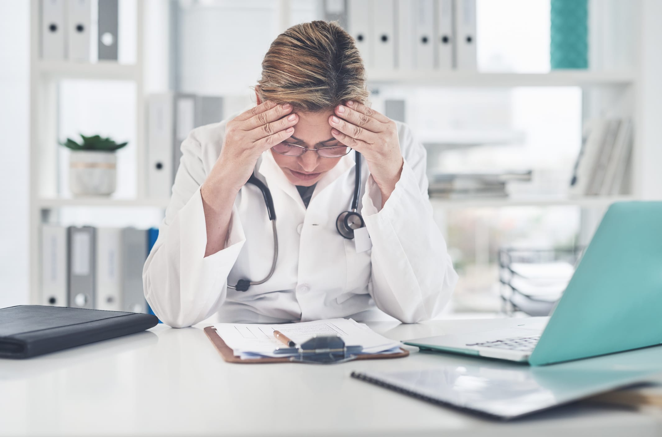 Cropped shot of a female doctor suffering with a headache while working in her office