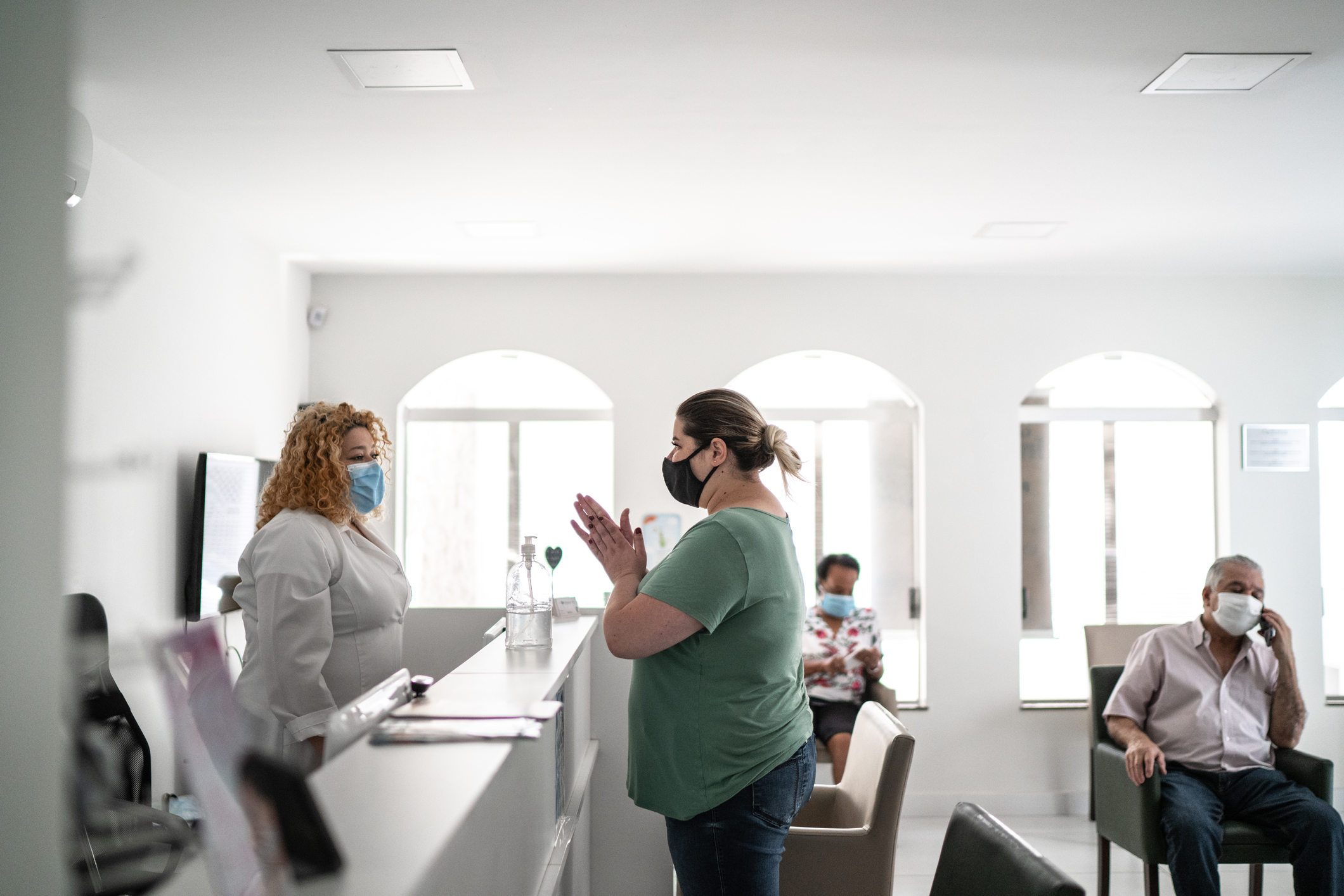 Patient arriving at medical clinic reception and using hand sanitizer