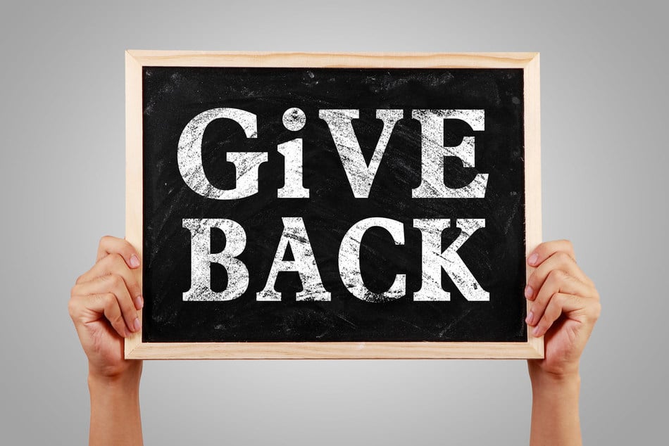 Person holding chalk board that says GIVE BACK.