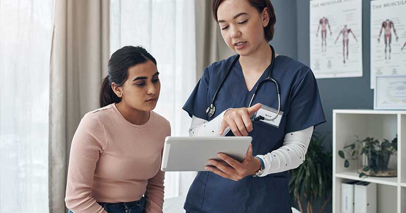 Nurse using data analytics software at bedside


