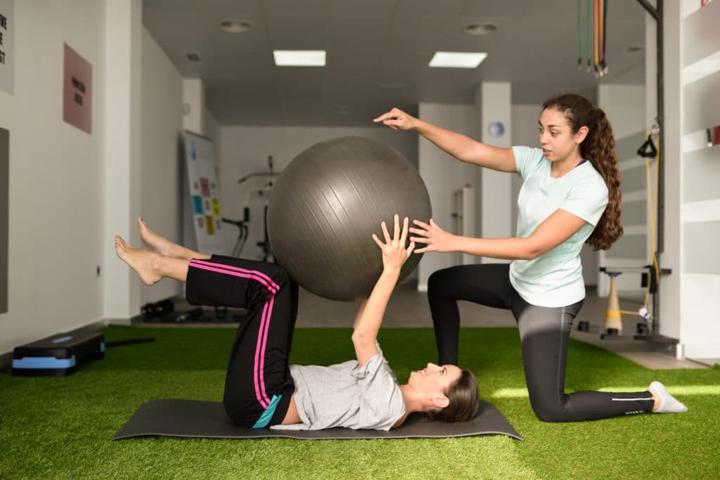 Physical therapist assisting young woman with exercise