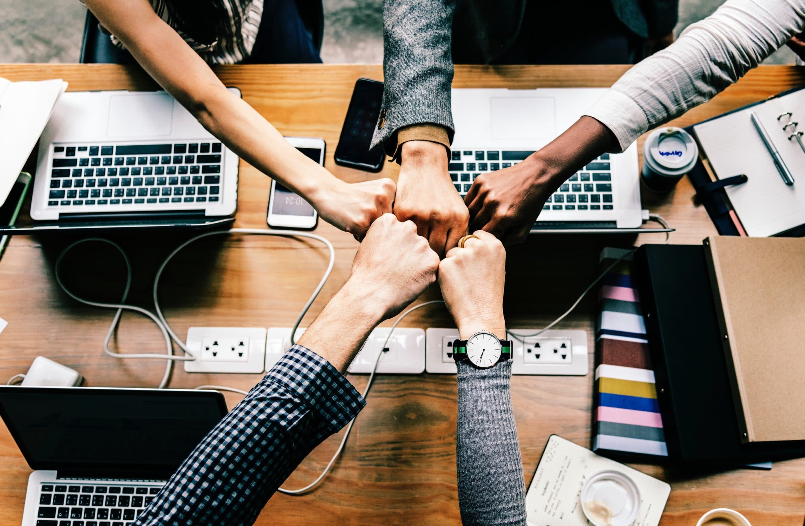 5 Team members at a desk with computer fist bumping