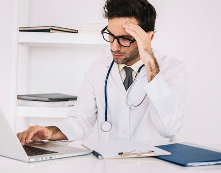 Stressed doctor looking at laptop