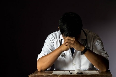 Male doctor with hands on his head.