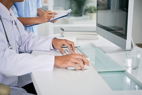 Doctor with nurse sitting in front of computer